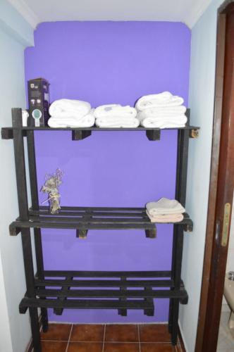 uma prateleira com toalhas dobradas numa parede roxa em Lo de Annie Depto 2 em Posadas