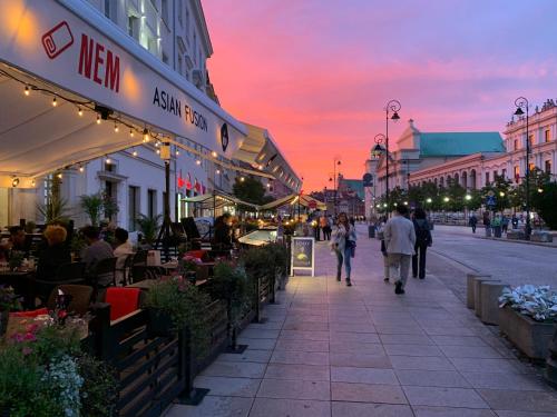 a group of people walking down a street at sunset at Jess Hotel & Spa Warsaw Old Town in Warsaw