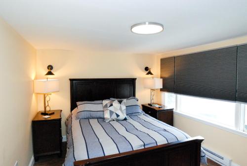 a bedroom with a bed with two lamps and a window at Maple Leaf Lodge in Schroon Lake