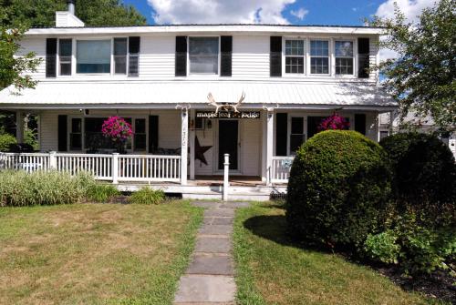 a white house with a white fence and pink flowers at Maple Leaf Lodge in Schroon Lake