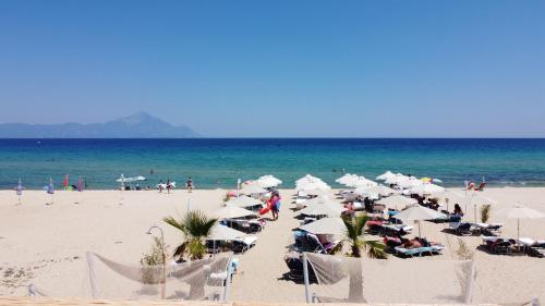 a beach with white umbrellas and people on the beach at Cocoon Hotel-Beach bar in Sarti