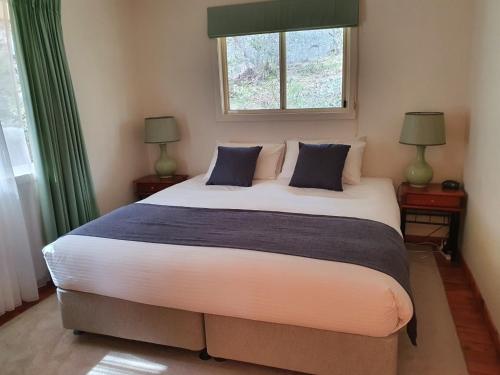 a bedroom with a large bed with two lamps and a window at Sancerre Estate in Ballandean