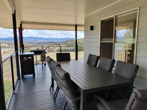 a dining table and chairs on a deck with a view at Sancerre Estate in Ballandean