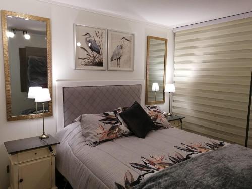 a bedroom with a bed with two lamps and two mirrors at Departamento Nuevo Papudo - Full equipado - 7 personas in Papudo