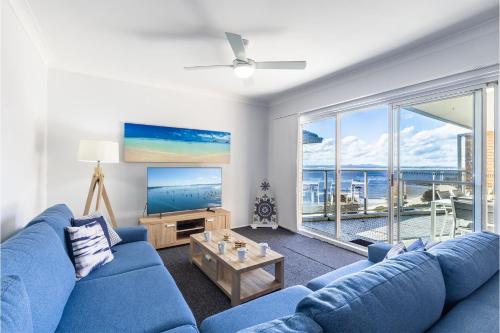 a living room with a blue couch and a tv at Kiah 12, 53 Victoria Pde - Panoramic water views, Wifi and Air Con in Nelson Bay