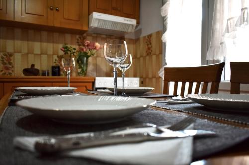 a table with plates and wine glasses on it at Κεντρικό και ευρύχωρο οροφοδιαμέρισμα in Kastoria