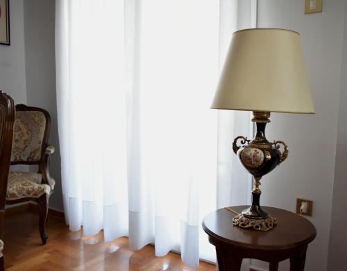 a lamp sitting on a table in front of a window at Κεντρικό και ευρύχωρο οροφοδιαμέρισμα in Kastoria