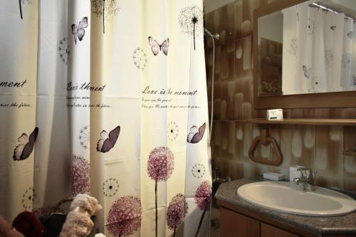 a bathroom with a sink and a shower curtain with butterflies at Κεντρικό και ευρύχωρο οροφοδιαμέρισμα in Kastoria