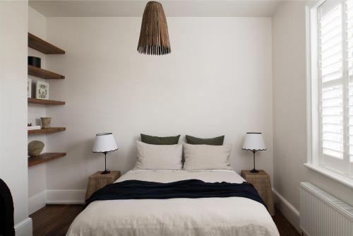 a bedroom with a bed with white walls and two lamps at Henry’s on Balfour - Historic understated luxury in Launceston
