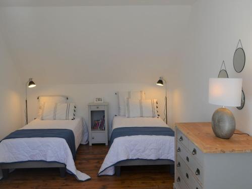 2 Betten in einem Schlafzimmer mit weißen Wänden und Holzböden in der Unterkunft Holiday Home Locquirec - BRE05104e-F in Locquirec