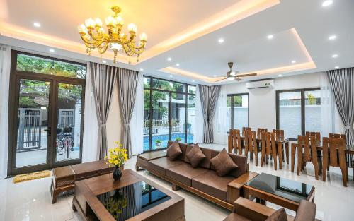 a living room with a couch and chairs and a chandelier at Sea Breeze Villa FLC sang trọng gần biển có bể bơi in Sầm Sơn