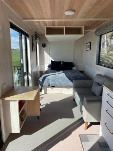 a room with a bed and a couch in a tiny house at Boutique Tiny House - Te Anau Country Accommodation in Te Anau