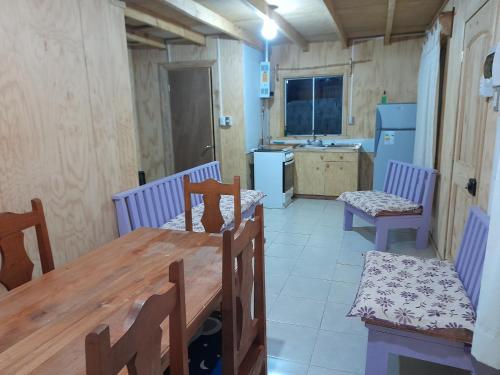 a dining room with a table and chairs and a kitchen at Cabañas Nehuen Coyan in Melipeuco