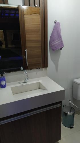 La salle de bains est pourvue d'un lavabo et d'une serviette violette suspendue. dans l'établissement Pousada Alto do Sossego, à Rio de Contas