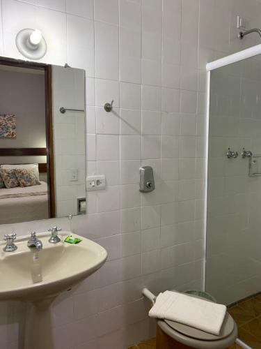 a bathroom with a sink and a shower with a mirror at Pousada do Grilo in Santo Antônio do Pinhal