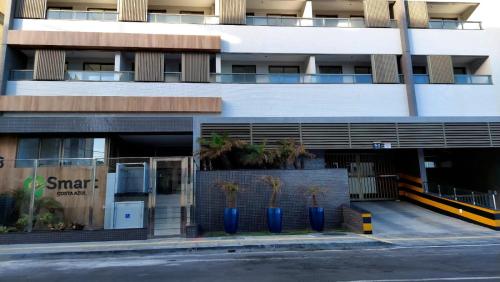 a building with blue vases with palm trees in it at Apartamento Smart Costa Azul in Salvador