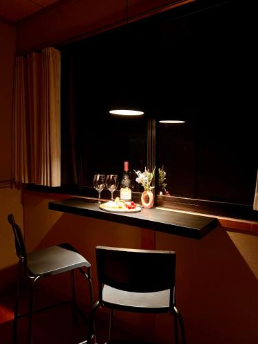 a bar with two chairs and a table with wine glasses at Yufuin Hoshinosato in Yufuin