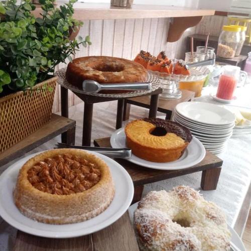 una tavola ricoperta con diversi tipi di torte e prodotti da forno di Pousada do Grilo a Santo Antônio do Pinhal