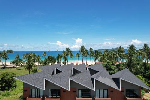 a house with a roof with the beach in the background at Nacpan Beach Resort Managed by H Hospitality Group in El Nido