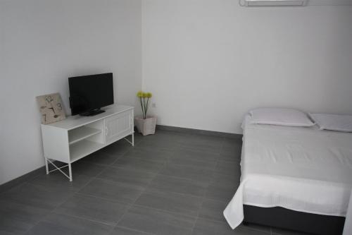 een slaapkamer met een bed en een tv op een kast bij Apartments Sonja in Pučišća