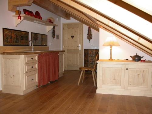 an attic kitchen with white cabinets and a table at Mansarda Dolomiti in Rasun di Sopra