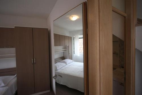 a small bedroom with a bed and a mirror at Apartments Sonja in Pučišća