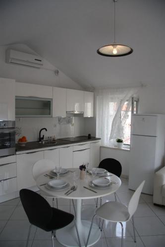 a white kitchen with a white table and chairs at Apartments Sonja in Pučišća