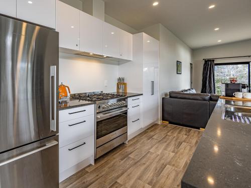 a kitchen with white cabinets and a stainless steel refrigerator at Modern Mountain Escape - Ohakune Holiday Home in Ohakune
