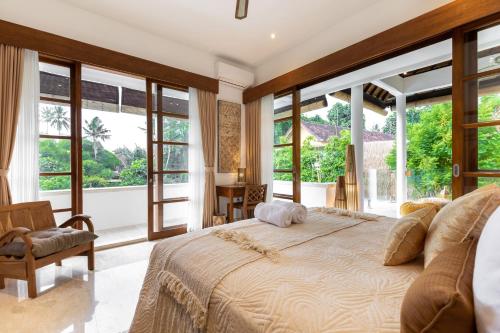a bedroom with a large bed and large windows at Luxury Villa in City Center w/ Natural Pool La Bohemia Residence Villas in Ubud