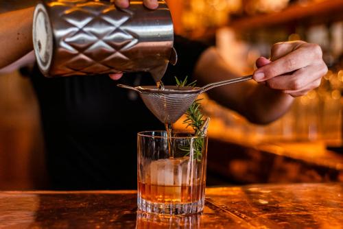 a person pouring a drink into a glass at The Tranquil House Inn in Manteo