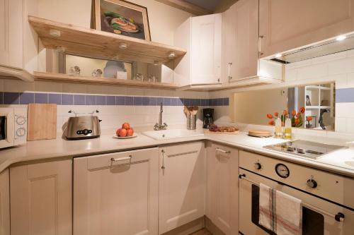 a kitchen with white cabinets and blue tiles at Romantic In Trendy Gracia in Barcelona