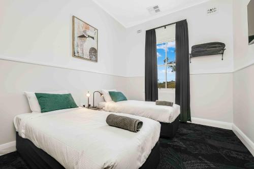 two beds in a room with a window at Royal Hotel Wyong in Wyong