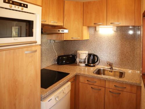 La cuisine est équipée de placards en bois, d'un évier et d'un four micro-ondes. dans l'établissement Appartement 2 pièces, 4/5 pers, accès pistes, parking, WiFi, animaux admis - FR-1-322-488, aux Orres