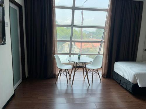 a table and two chairs in a room with a window at King's Lane Ipoh in Ipoh