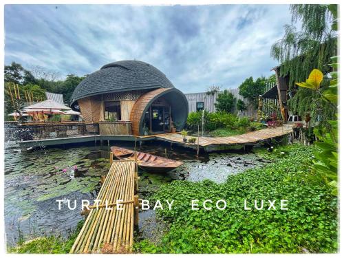 a circular building with a bridge over a body of water at Turtle Bay Eco Luxe Hua Hin in Khao Tao