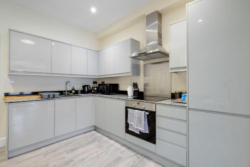 una cocina blanca con armarios y electrodomésticos blancos en The Norfolk - comfortable 1 Bedroom Apts with Parking, Maidenhead by 360Stays, en Maidenhead