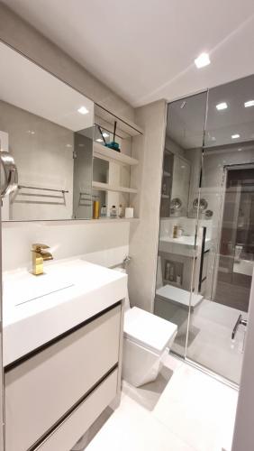 a white bathroom with a sink and a shower at Apartamento completo na praia brava in Itajaí