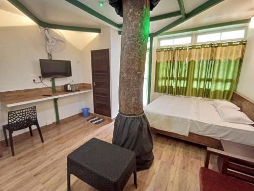 a room with a bed and a tree in it at SpiceBuds FarmStay - Ramakkalmedu in Idukki