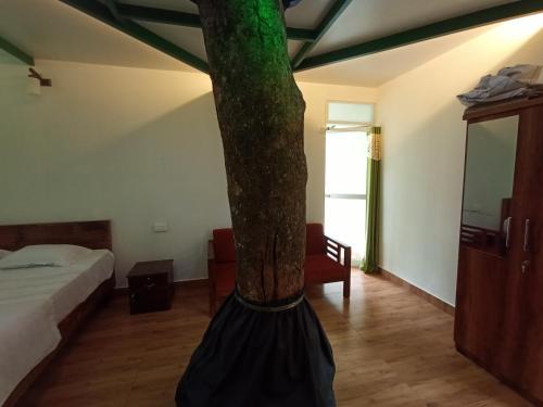 a room with a bed and a tree in it at SpiceBuds FarmStay - Ramakkalmedu in Idukki