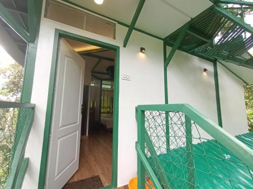 une porte d'entrée d'une maison avec une balustrade verte dans l'établissement SpiceBuds FarmStay - Ramakkalmedu, à Idukki