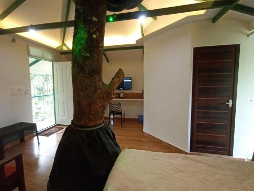 a room with a bed and a tree in it at SpiceBuds FarmStay - Ramakkalmedu in Idukki