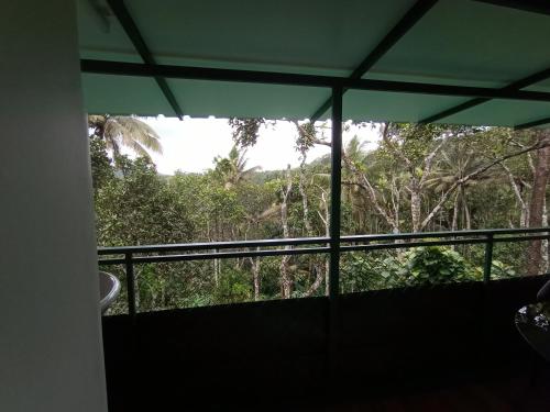 a balcony with a view of a forest at SpiceBuds FarmStay - Ramakkalmedu in Idukki