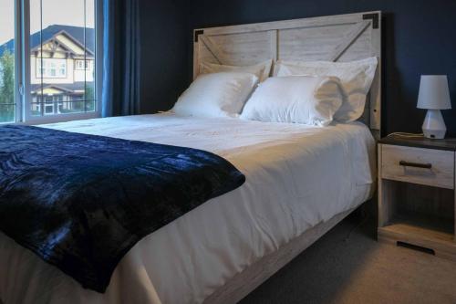 a bedroom with a large white bed with a window at Entire Home Near Calgary, Canmore & Banff Rocky Mountain Gateway in Cochrane