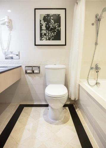 a white bathroom with a toilet and a bath tub at Eaton HK in Hong Kong