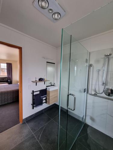uma casa de banho com um chuveiro e uma cabina de duche em vidro. em Colonial Motel em Twizel