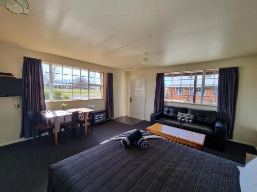a bedroom with a bed and a table and a couch at Colonial Motel in Twizel