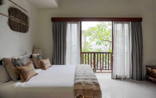 1 dormitorio con cama grande y ventana grande en Aroha Boutique Villas, en Seminyak