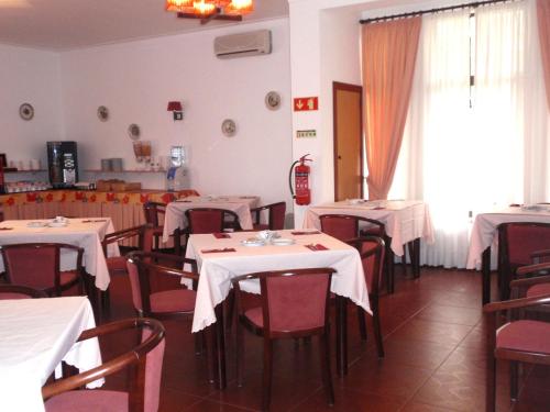 un restaurant avec des tables, des chaises et des nappes blanches dans l'établissement Hotel Ouro Verde, à Praia da Vieira