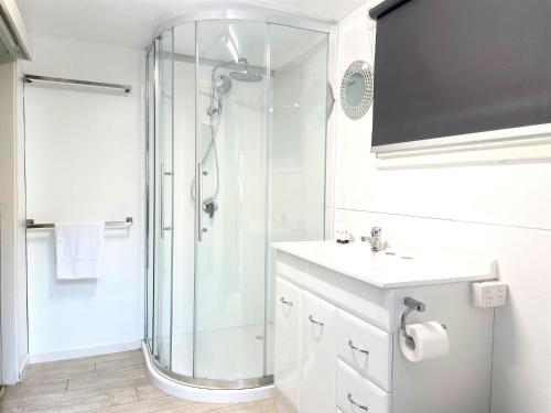 uma casa de banho branca com um chuveiro e um lavatório. em Esk Caravan Park & Rail Trail Motel em Esk