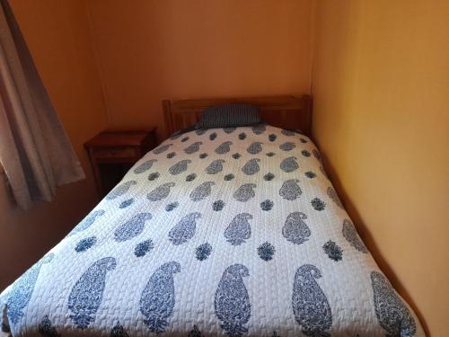 a bed with a blue and white quilt on it at Refugio de montaña in Melipeuco